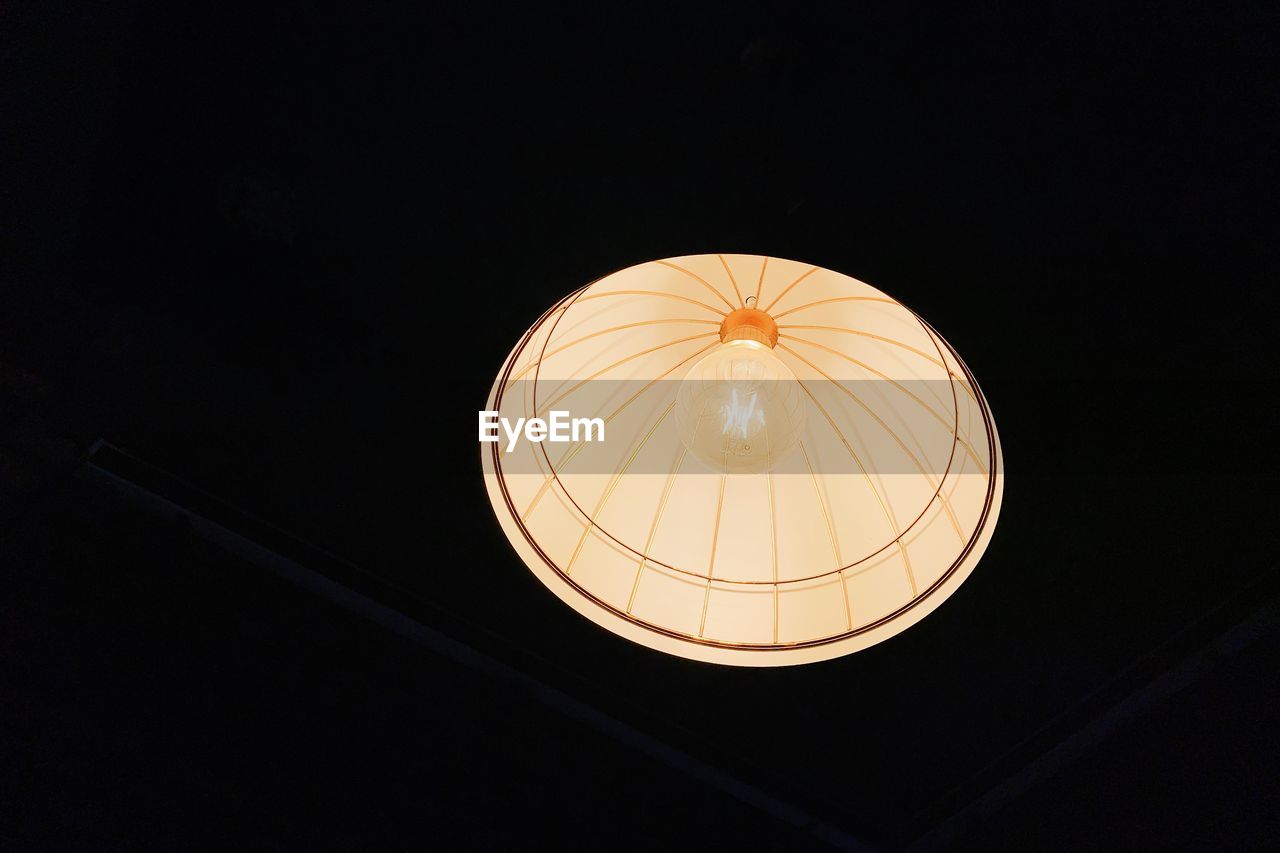 Low angle view of illuminated pendant light on black background