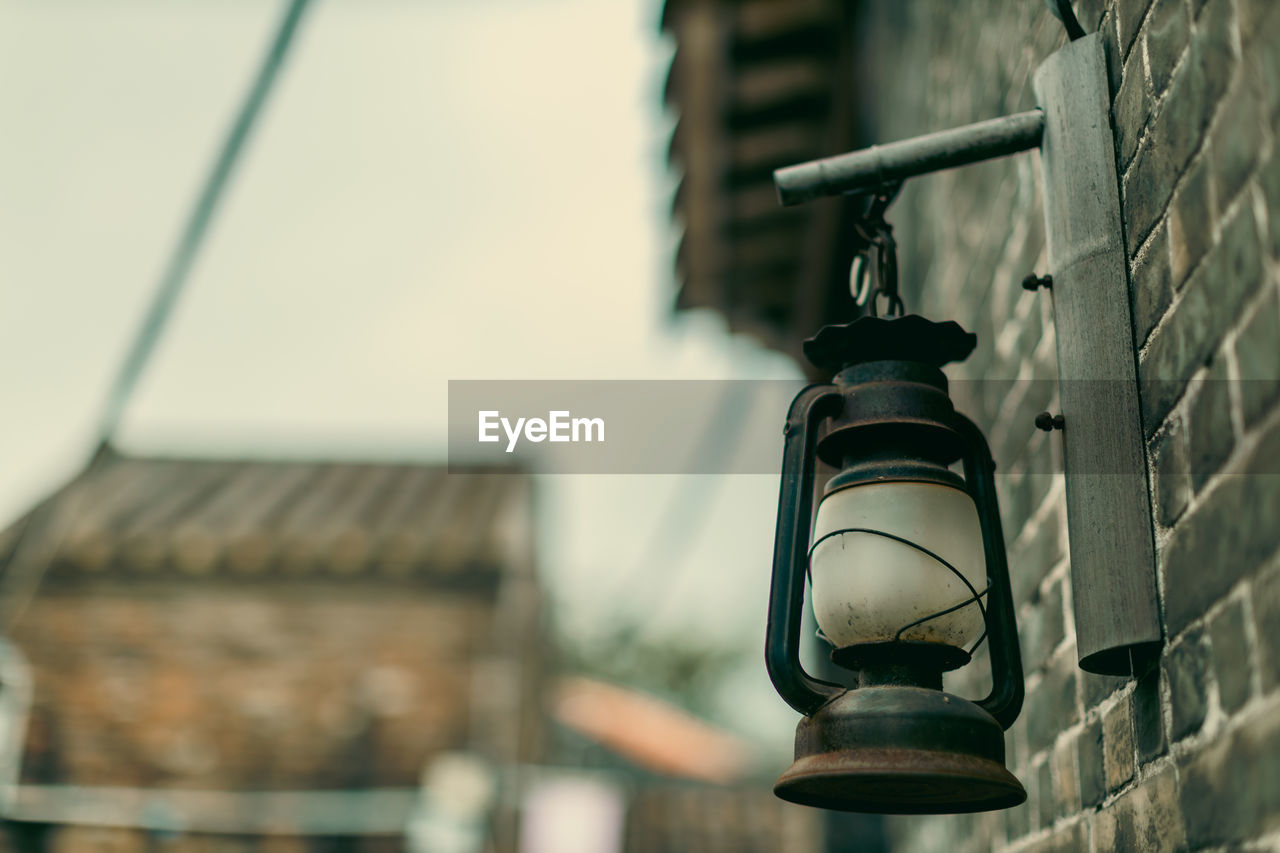 architecture, built structure, building exterior, light, no people, black, lighting equipment, focus on foreground, camera, lighting, blue, low angle view, day, city, street, building, outdoors, white, hanging, street light, wall - building feature, close-up, selective focus, metal, iron