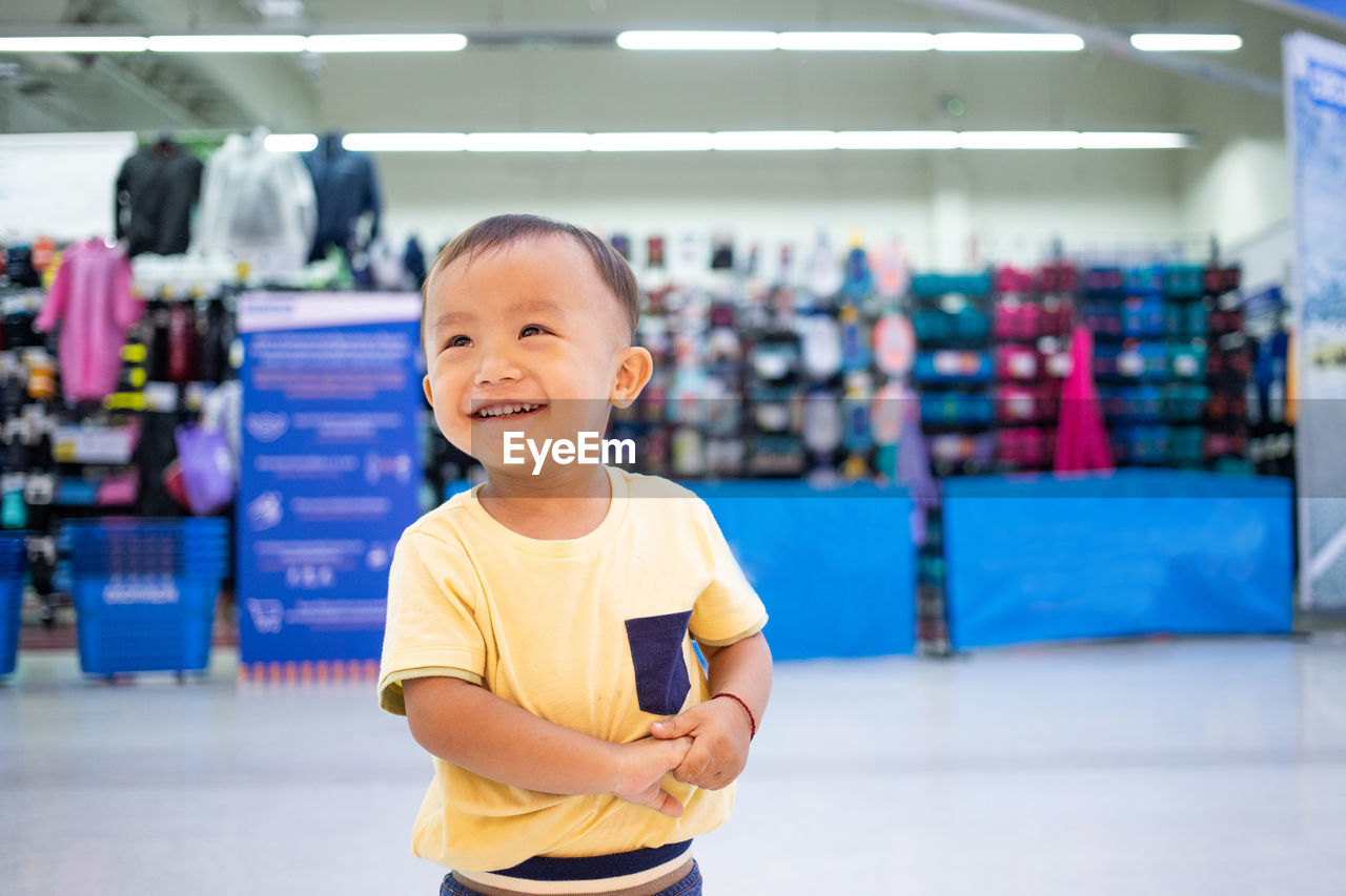 PORTRAIT OF A SMILING BOY STANDING IN FRONT OF MAN