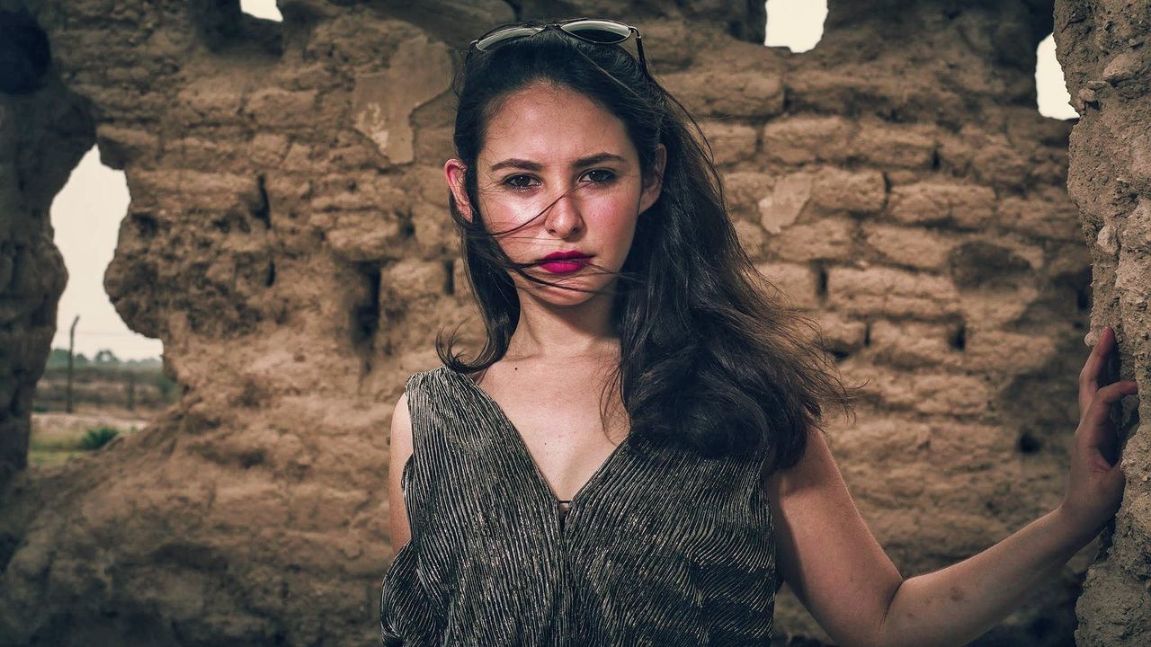 Portrait of beautiful young woman standing against stone wall