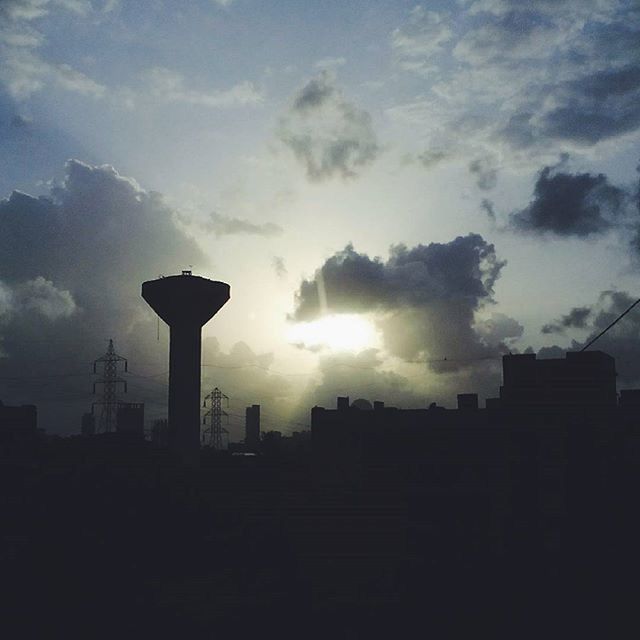 SILHOUETTE OF BUILDINGS AGAINST CLOUDY SKY