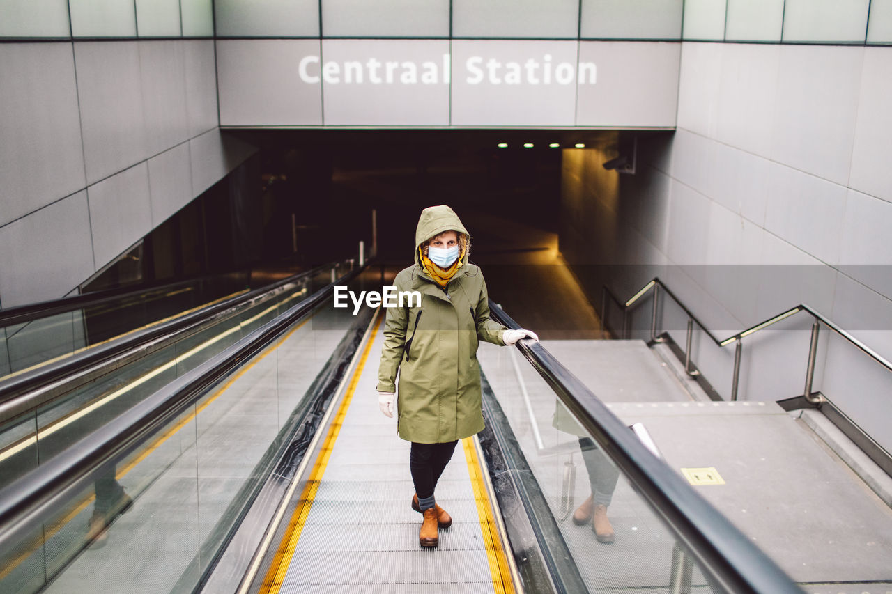 Portrait of woman wearing mask standing on escalator at subway station