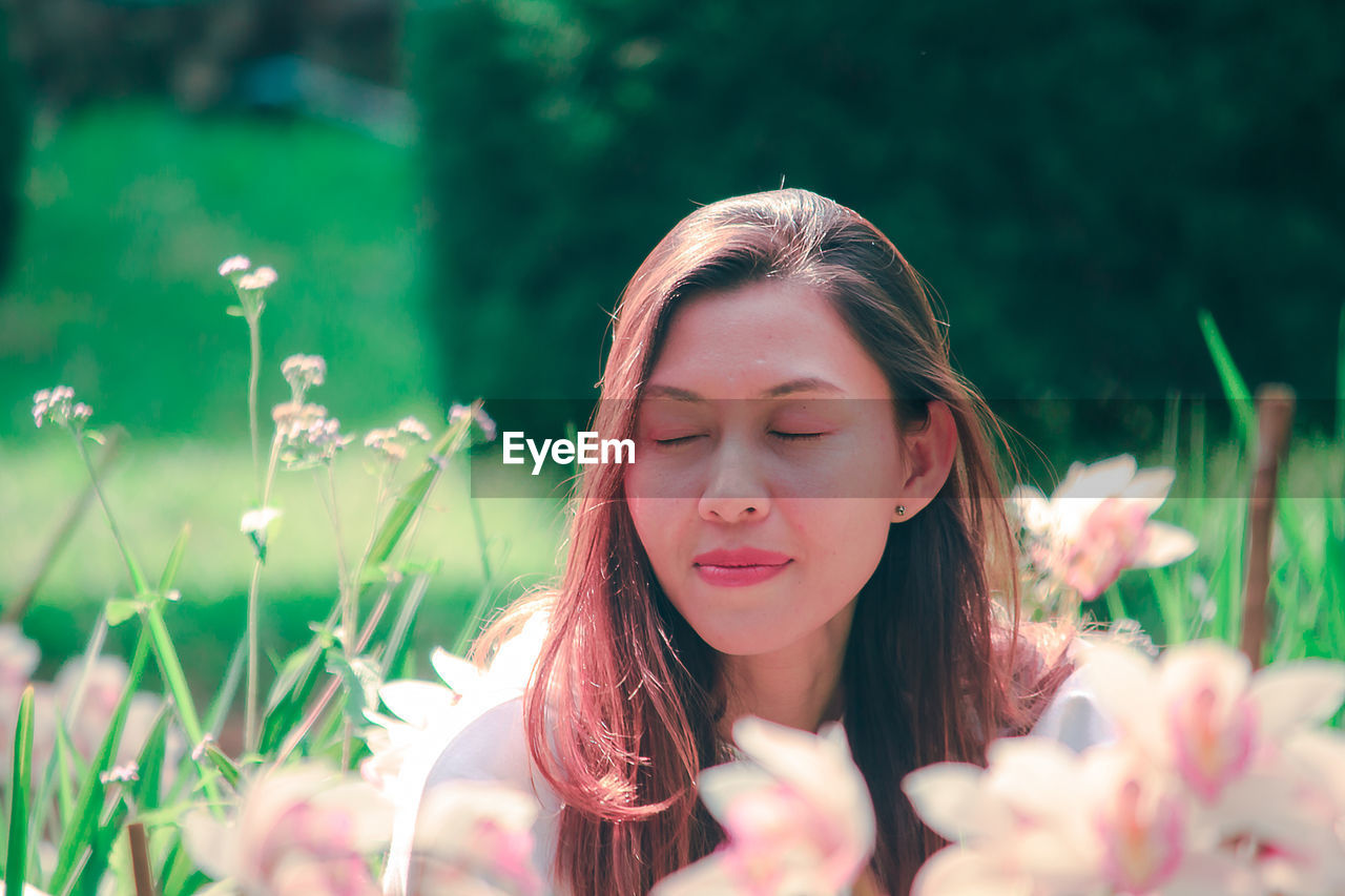 Close-up of woman with closed eyes by pink flowers