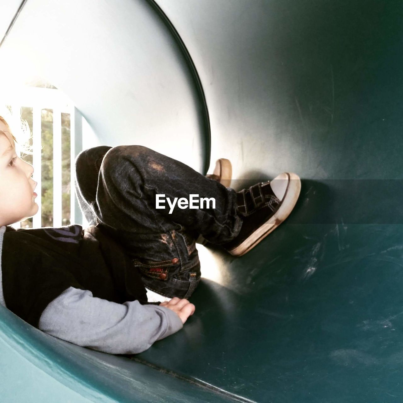 Side view of boy playing in tunnel at playground