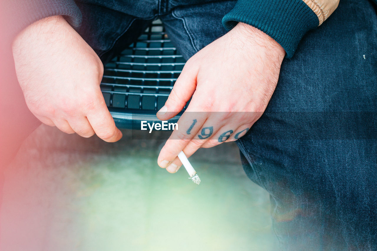 Midsection of man holding cigarette