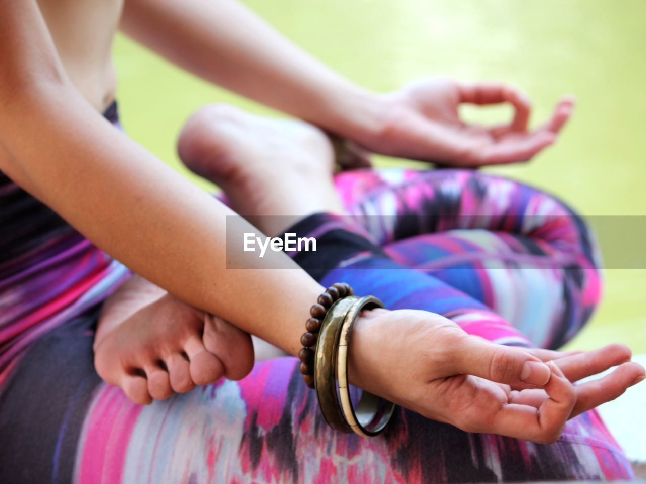 Low section of woman practicing yoga by lake