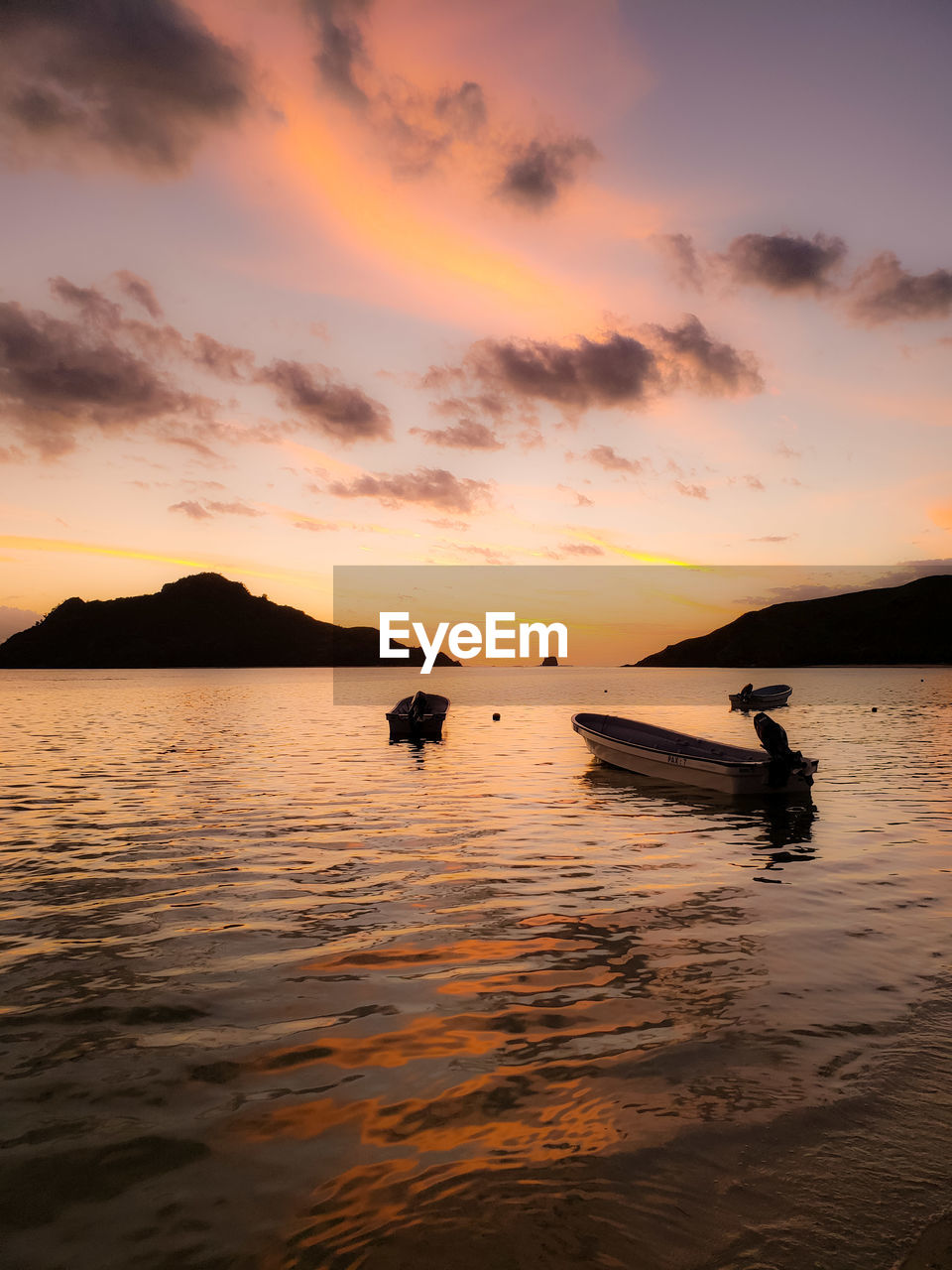 Silhouette boats moored in sea against sky during sunset