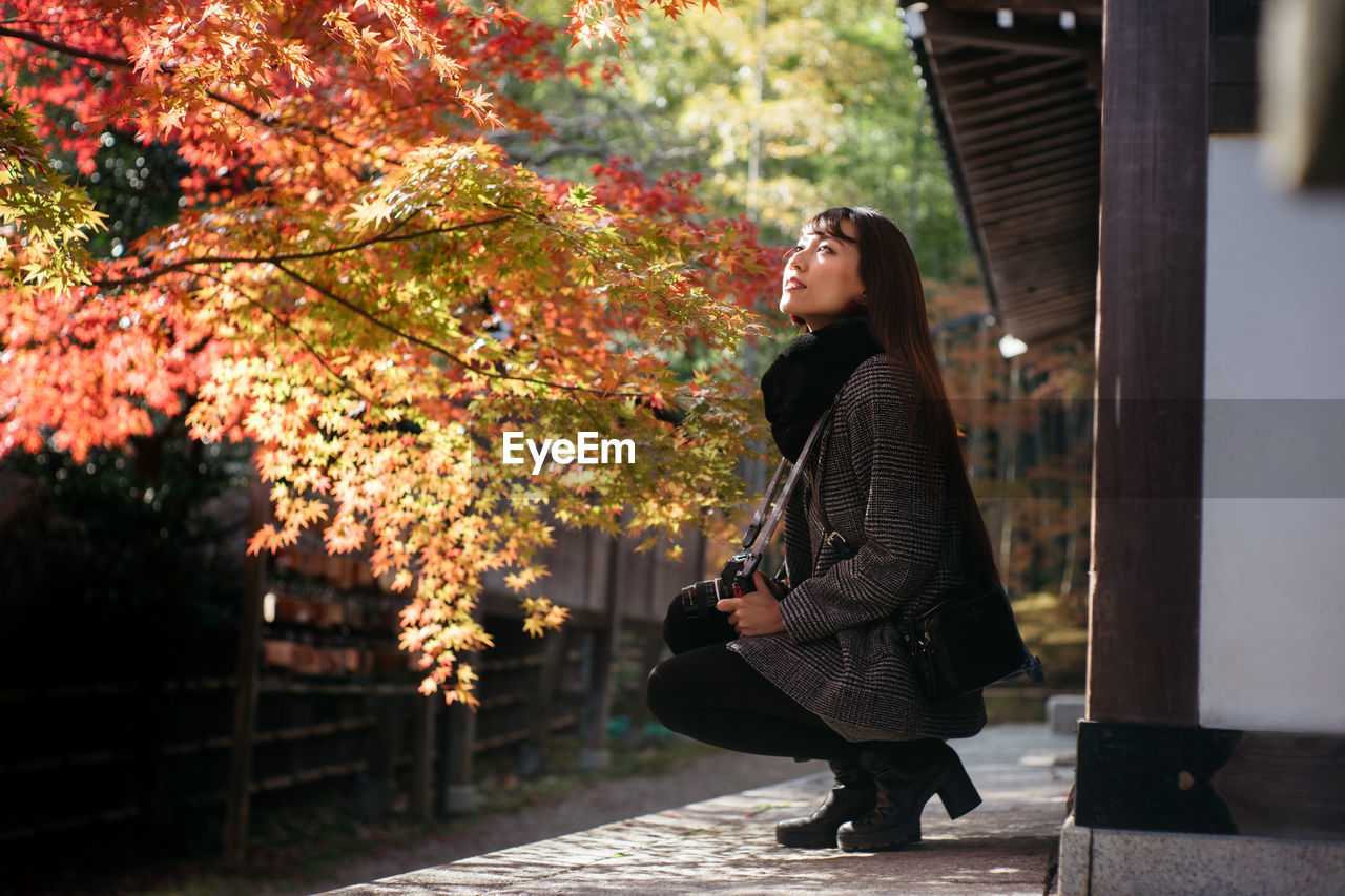 FULL LENGTH OF WOMAN STANDING BY TREE