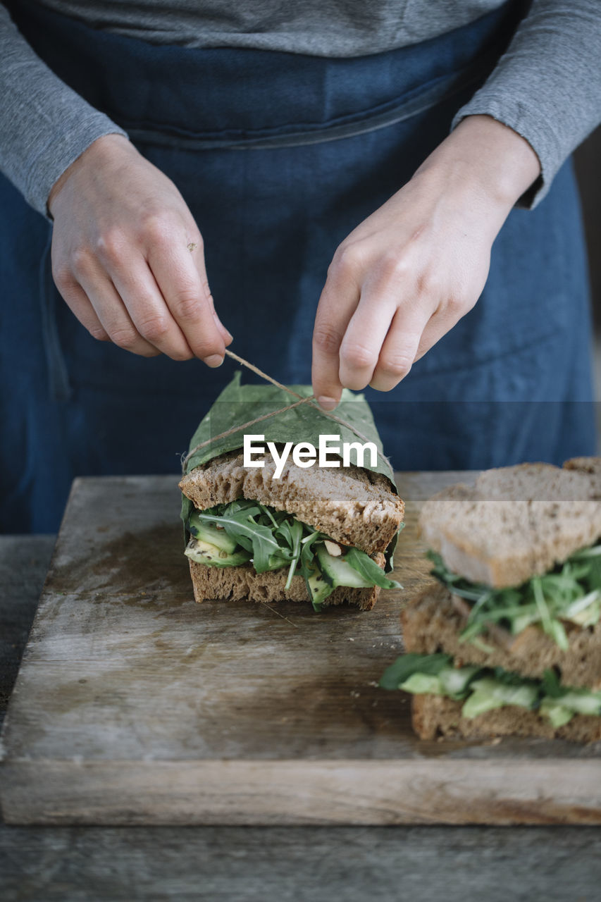 Midsection of woman making sandwich on cutting board at home