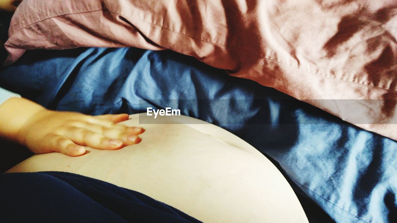 MIDSECTION OF WOMAN LYING ON BED