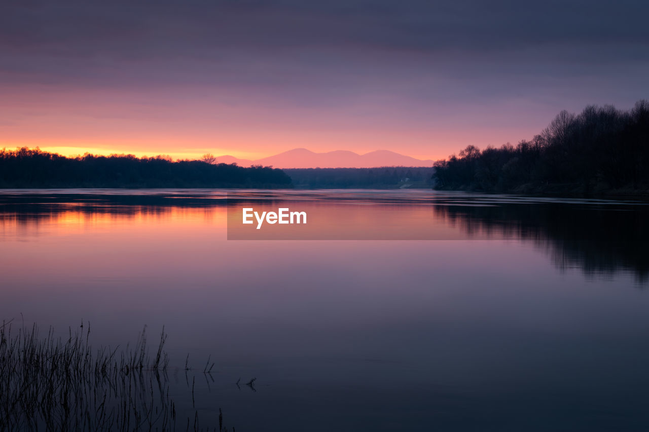 Scenic view of river against sky during sunset