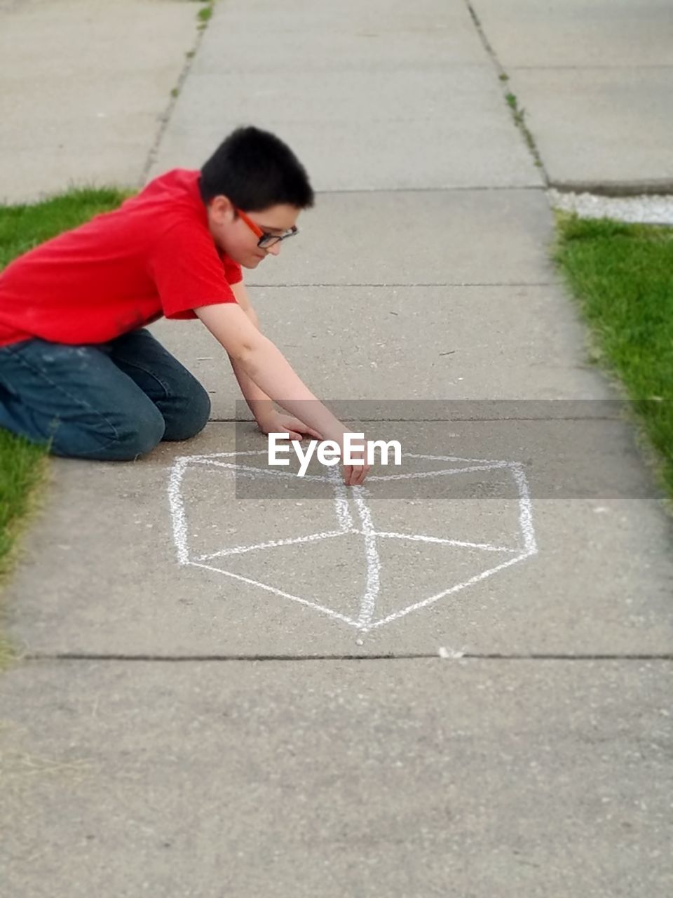 Side view of boy drawing on footpath