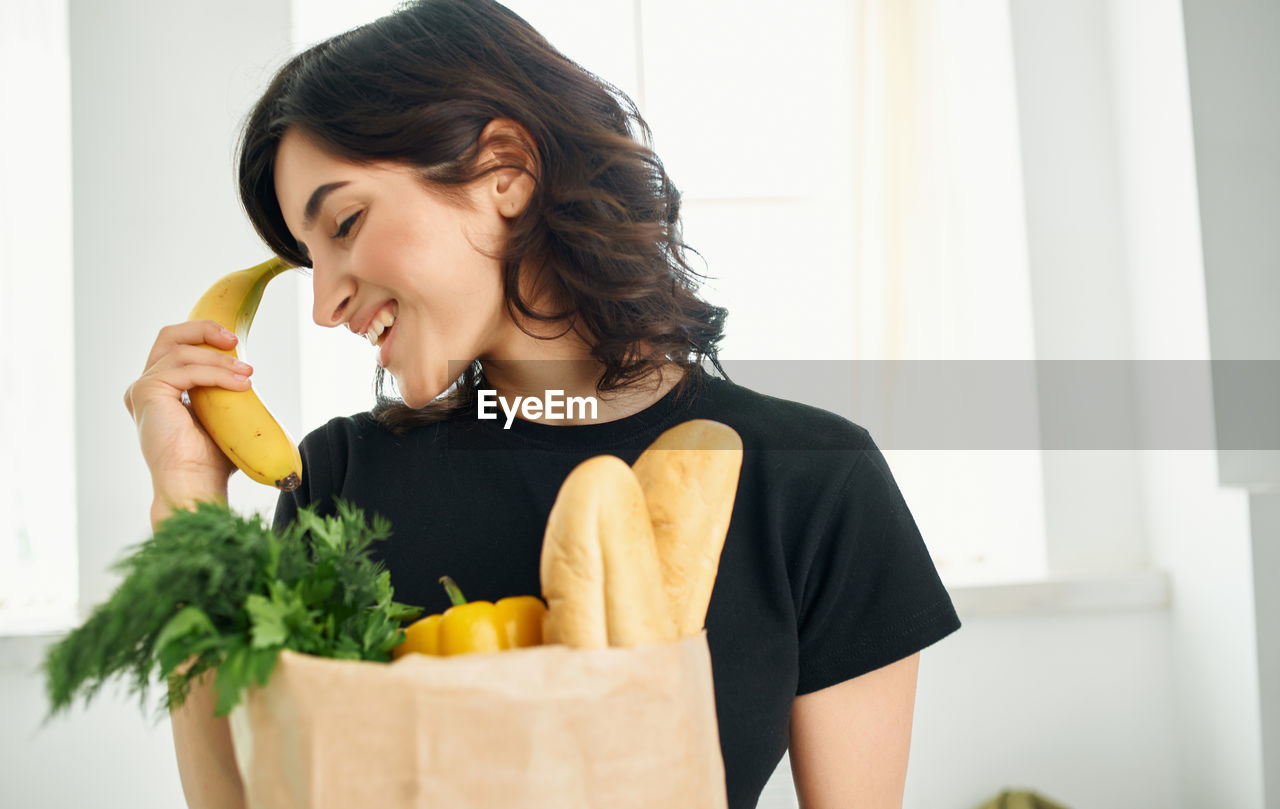 portrait of smiling young woman holding food at home
