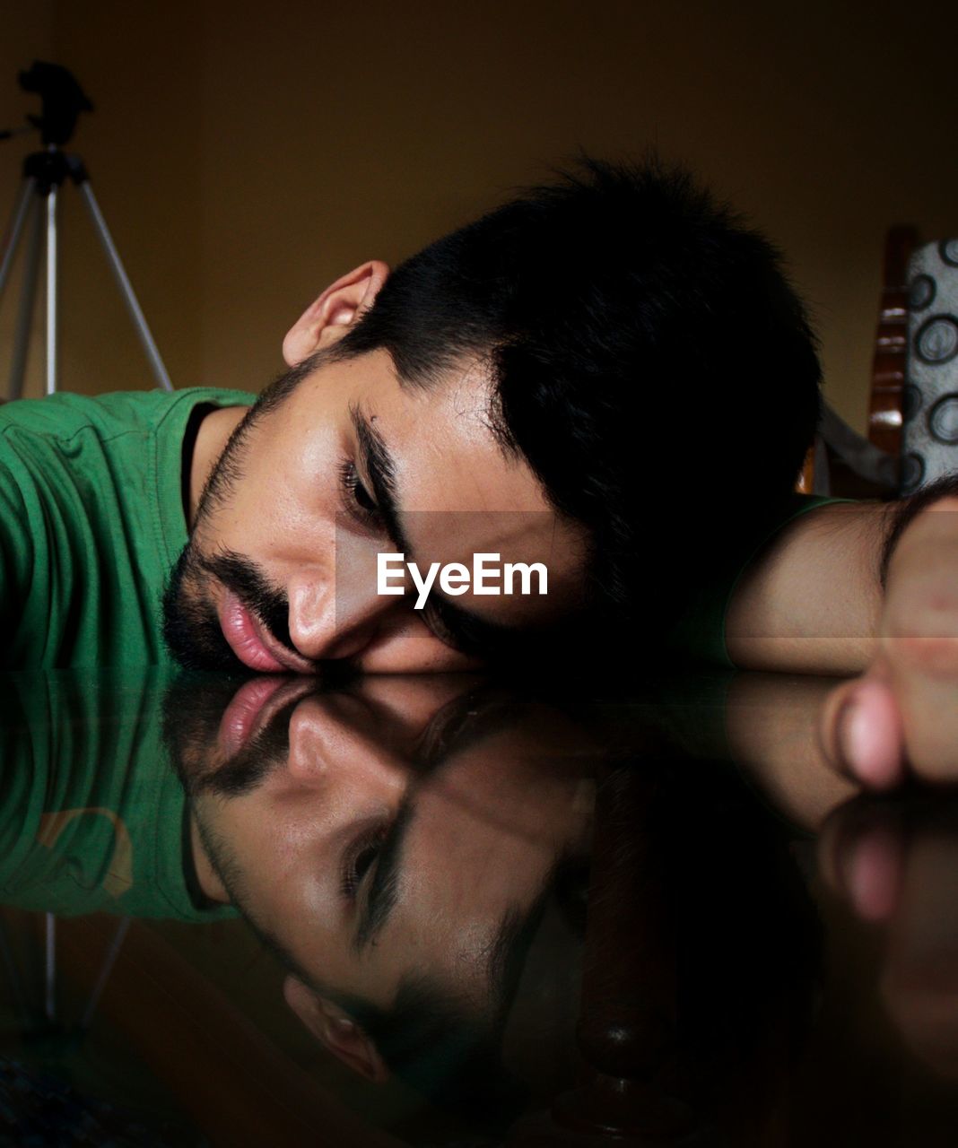 Close-up of sad young man lying on table at home