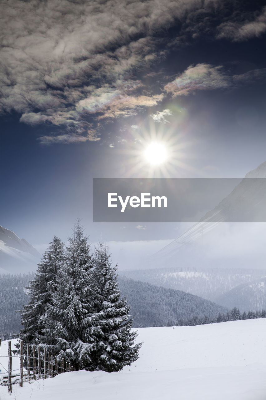 Scenic view of snow covered mountains against bright sun