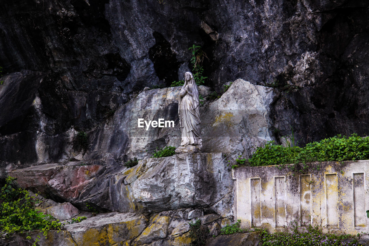 Statue of mother mary on rock