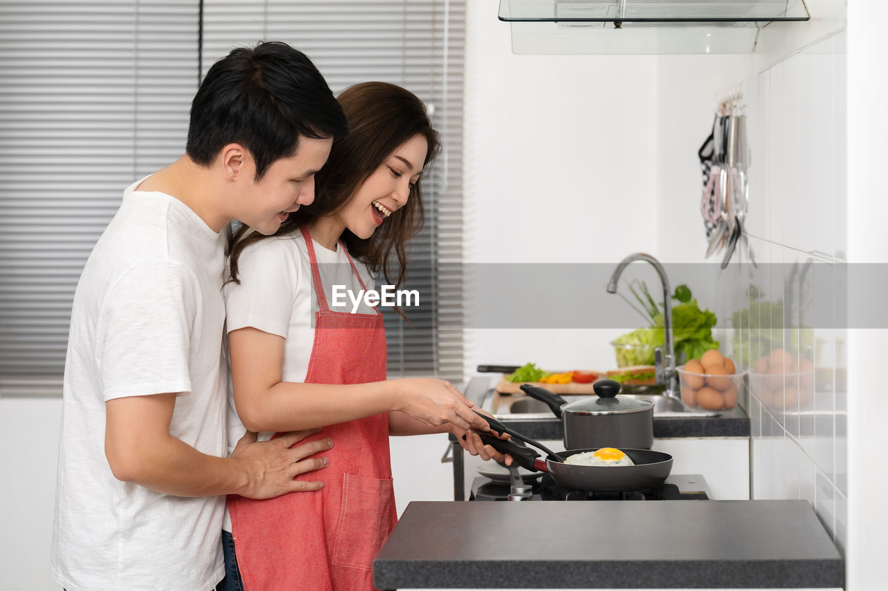 side view of young woman preparing food in kitchen