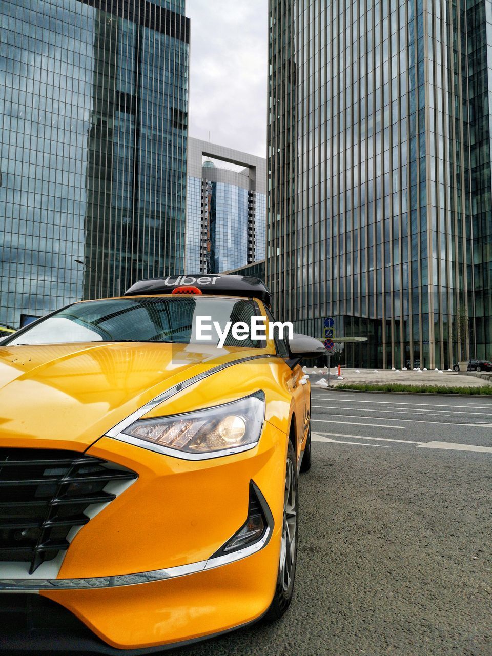 YELLOW CAR ON STREET BY BUILDINGS