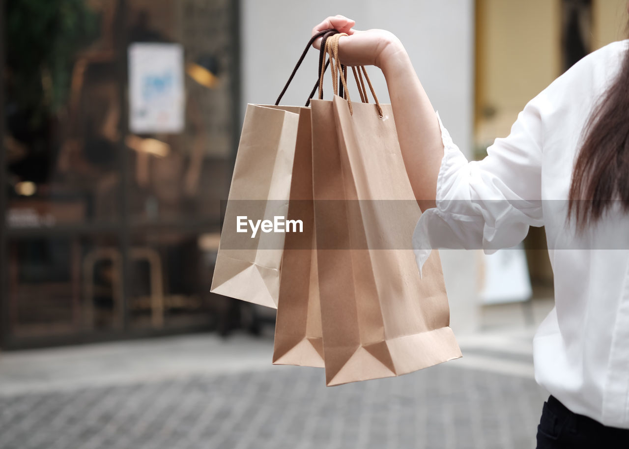 Midsection of woman holding shopping bags