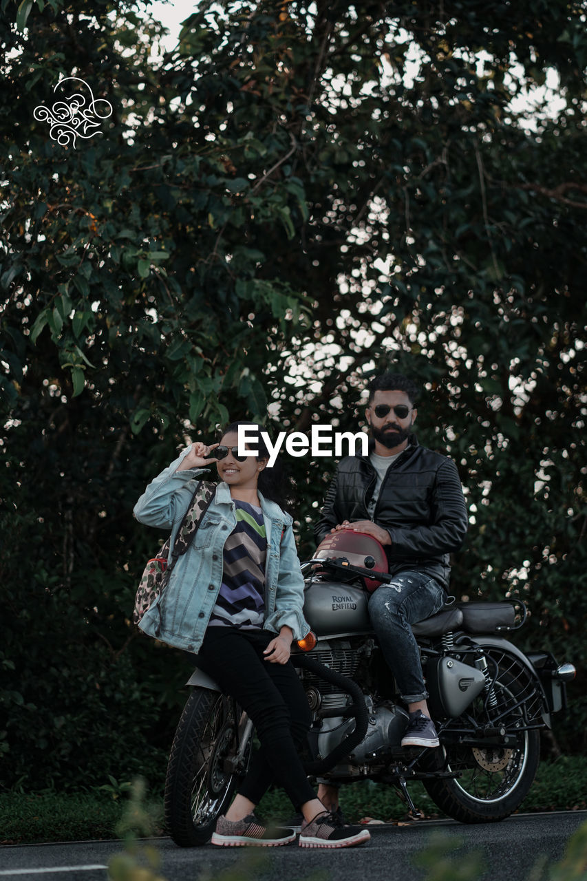 FULL LENGTH OF YOUNG MAN AND WOMAN AGAINST TREE