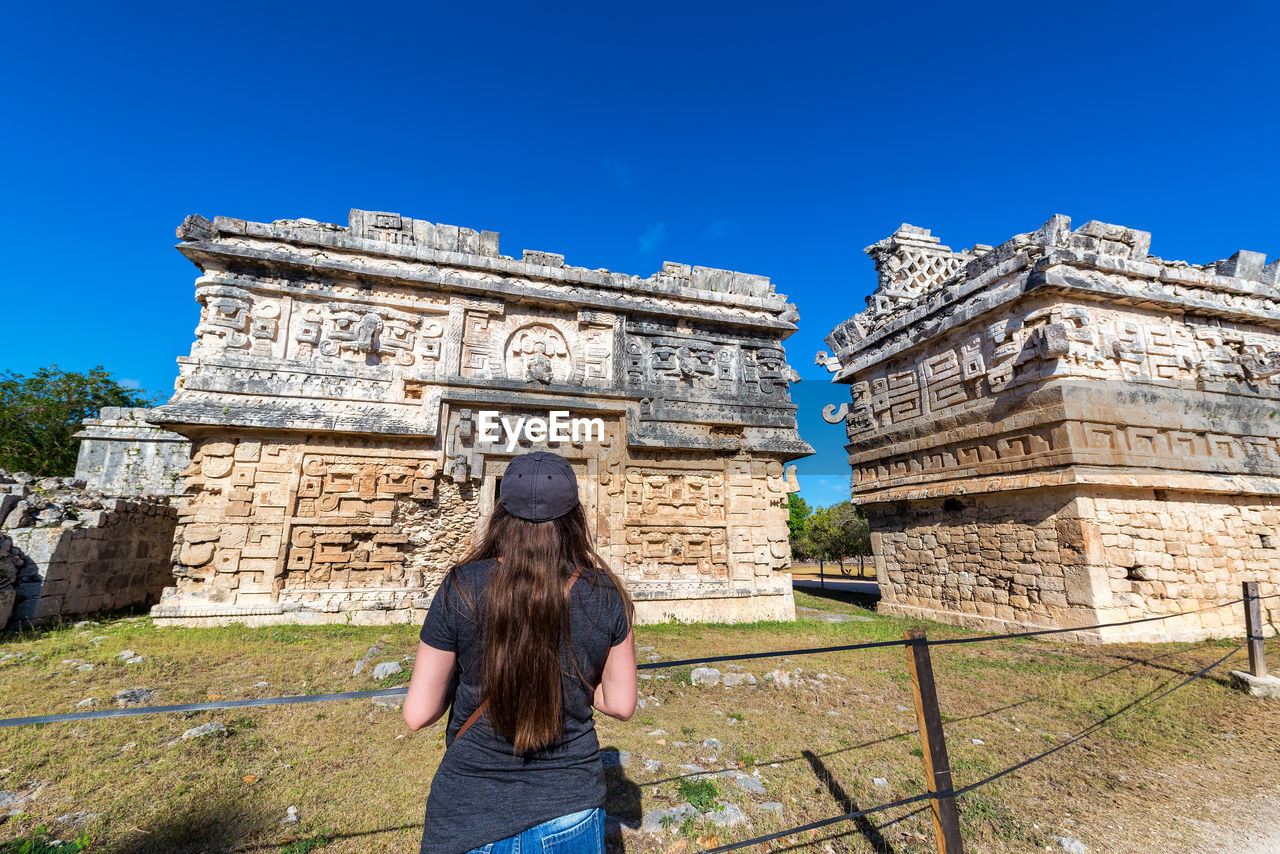 Rear view of woman standing at chichen itza during sunny day