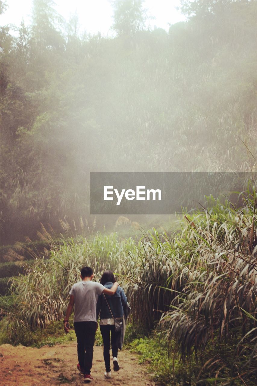 High angle view of man and woman walking in field during foggy weather