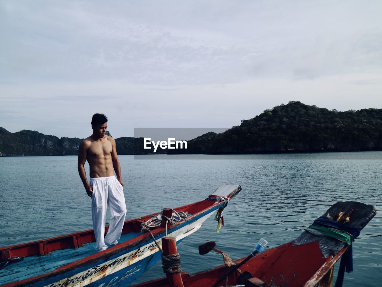 Man standing on the boat and looking at sea against sky