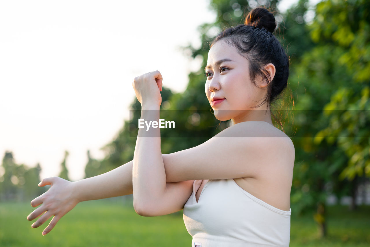 side view of young woman exercising against trees