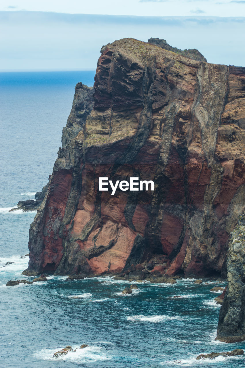 Rock formation on sea shore against sky