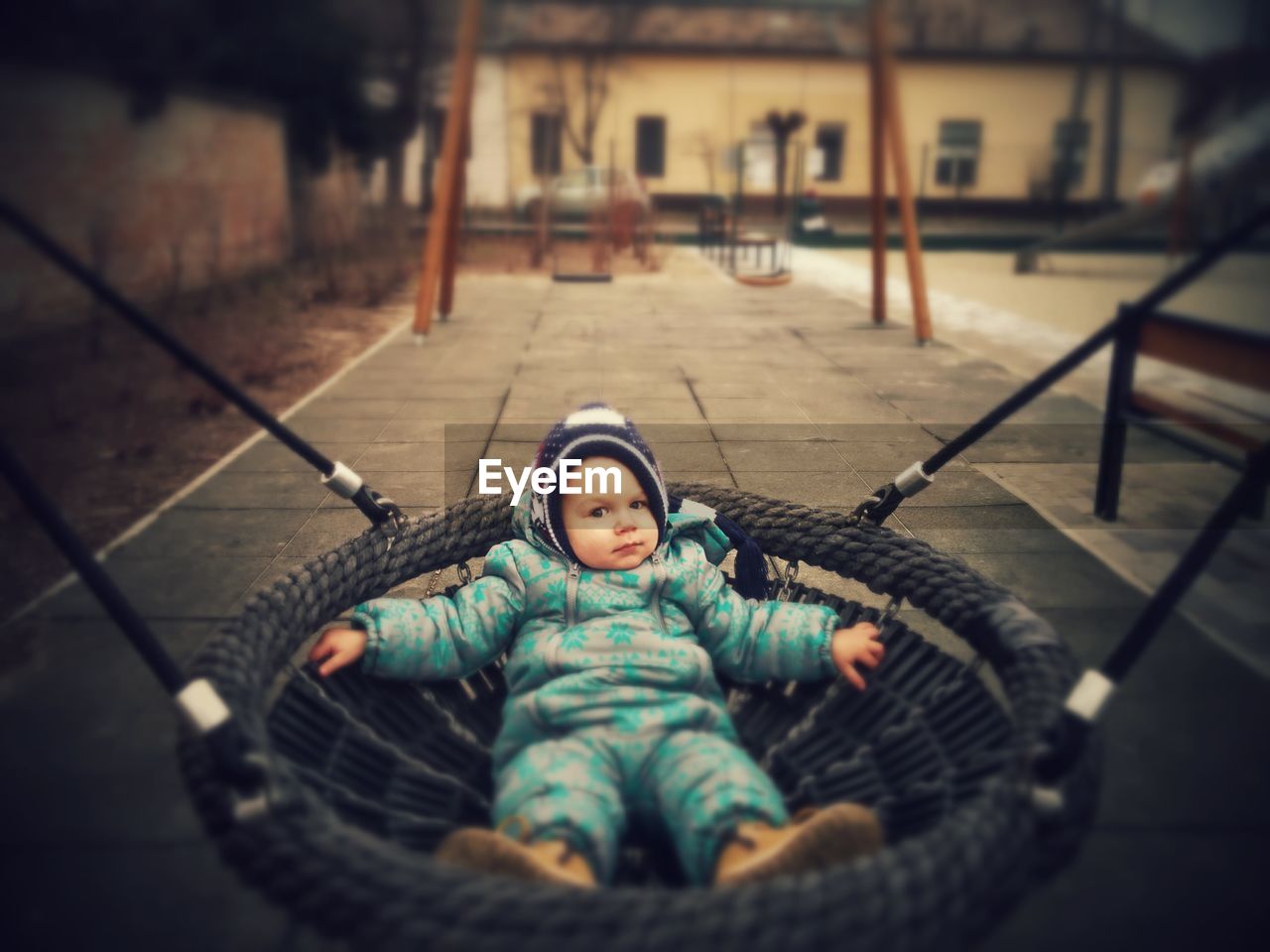 High angle view of boy lying on swing at playground