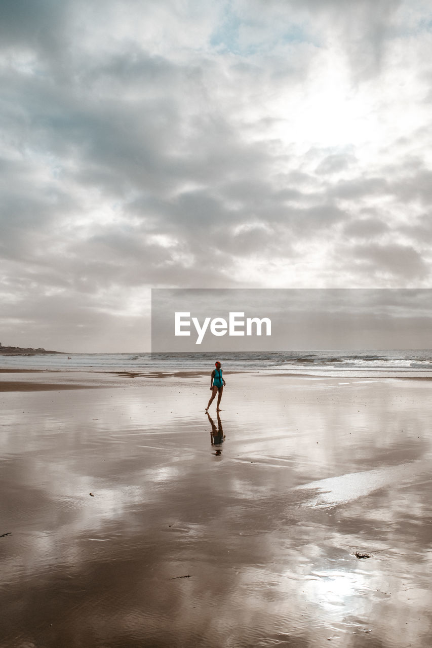 full length of boy running on beach against sky