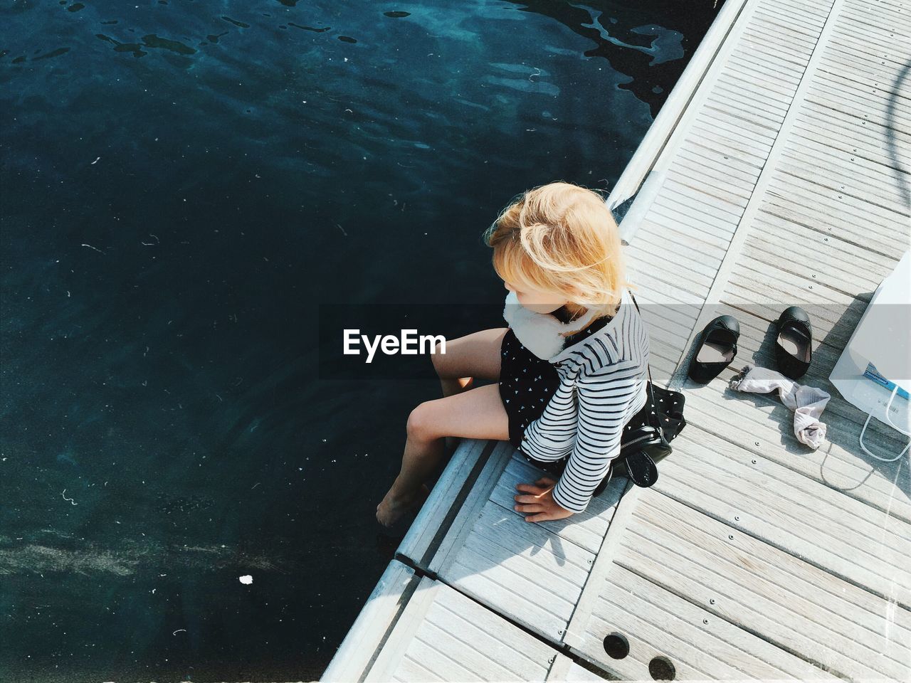 High angle view of girl sitting on pier