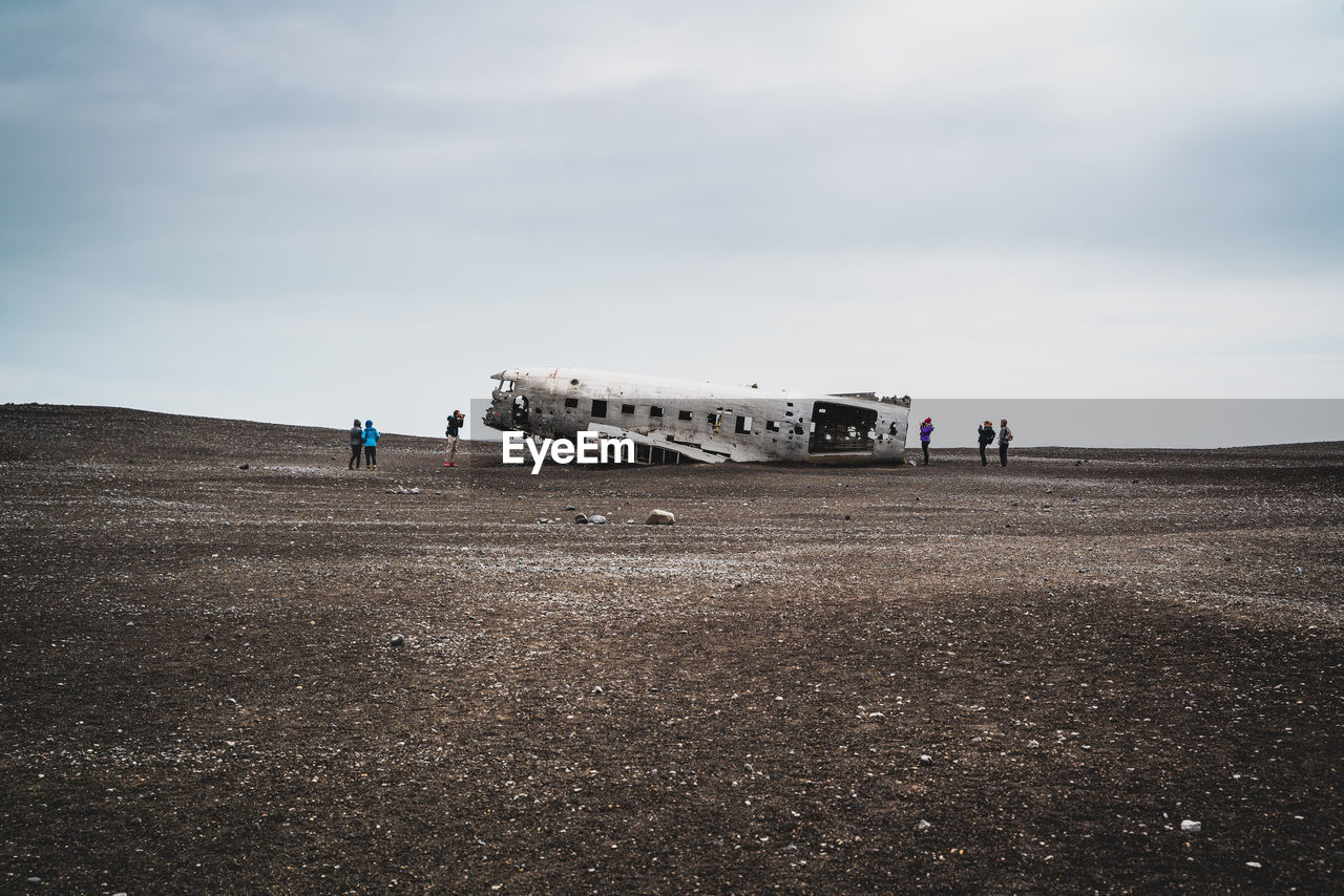 Mid distance view of people looking at abandoned airplane