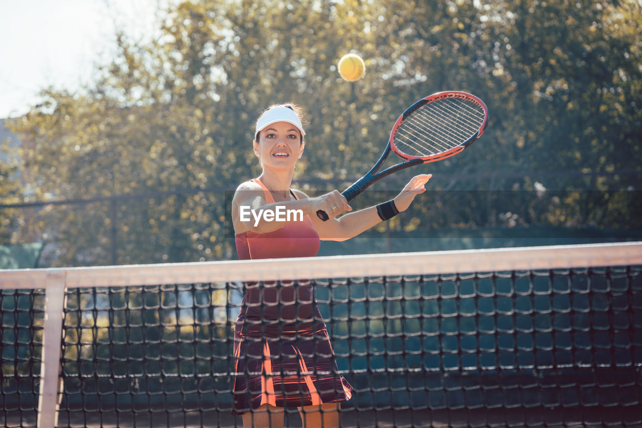 Woman playing with ball in tennis court