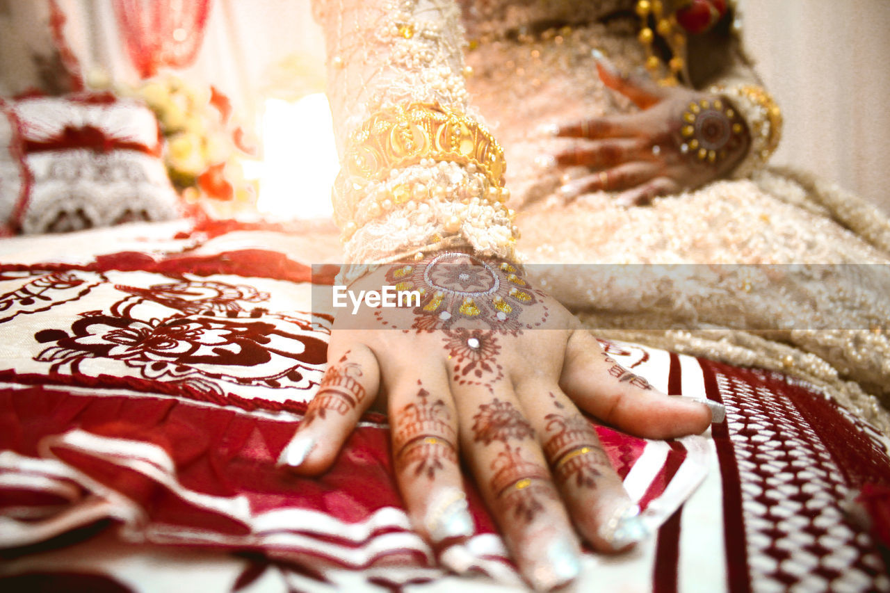 CLOSE-UP OF WOMAN HAND WITH TATTOO ON BED AT HOME