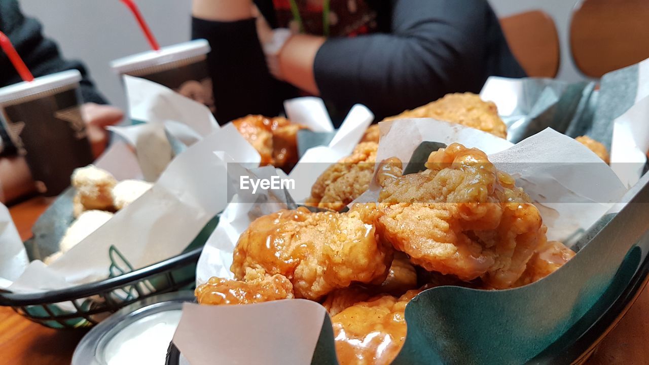 Close-up of deep fried chicken against woman sitting in restaurant