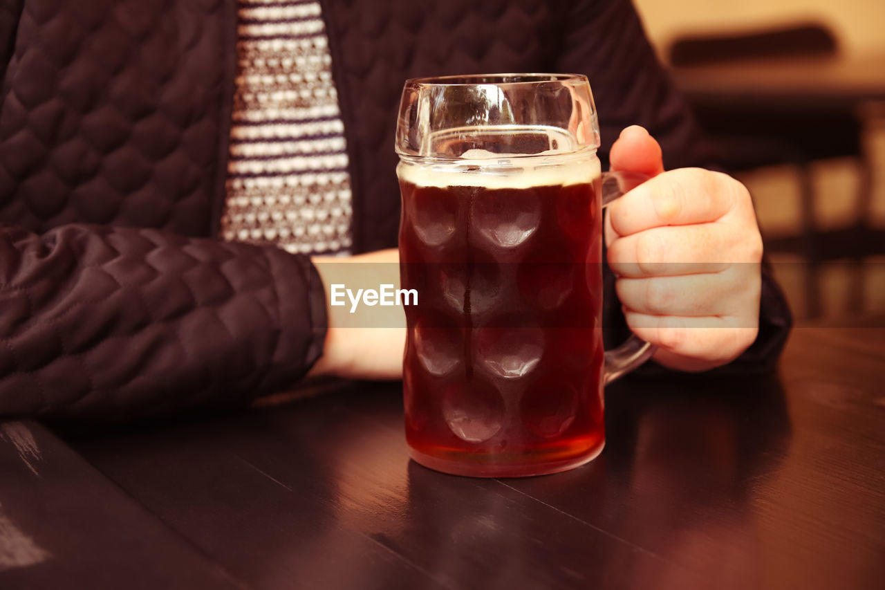 Dark beer. mug of dark beer. closeup of two hands clinking beer stein glasses. people, woman or man