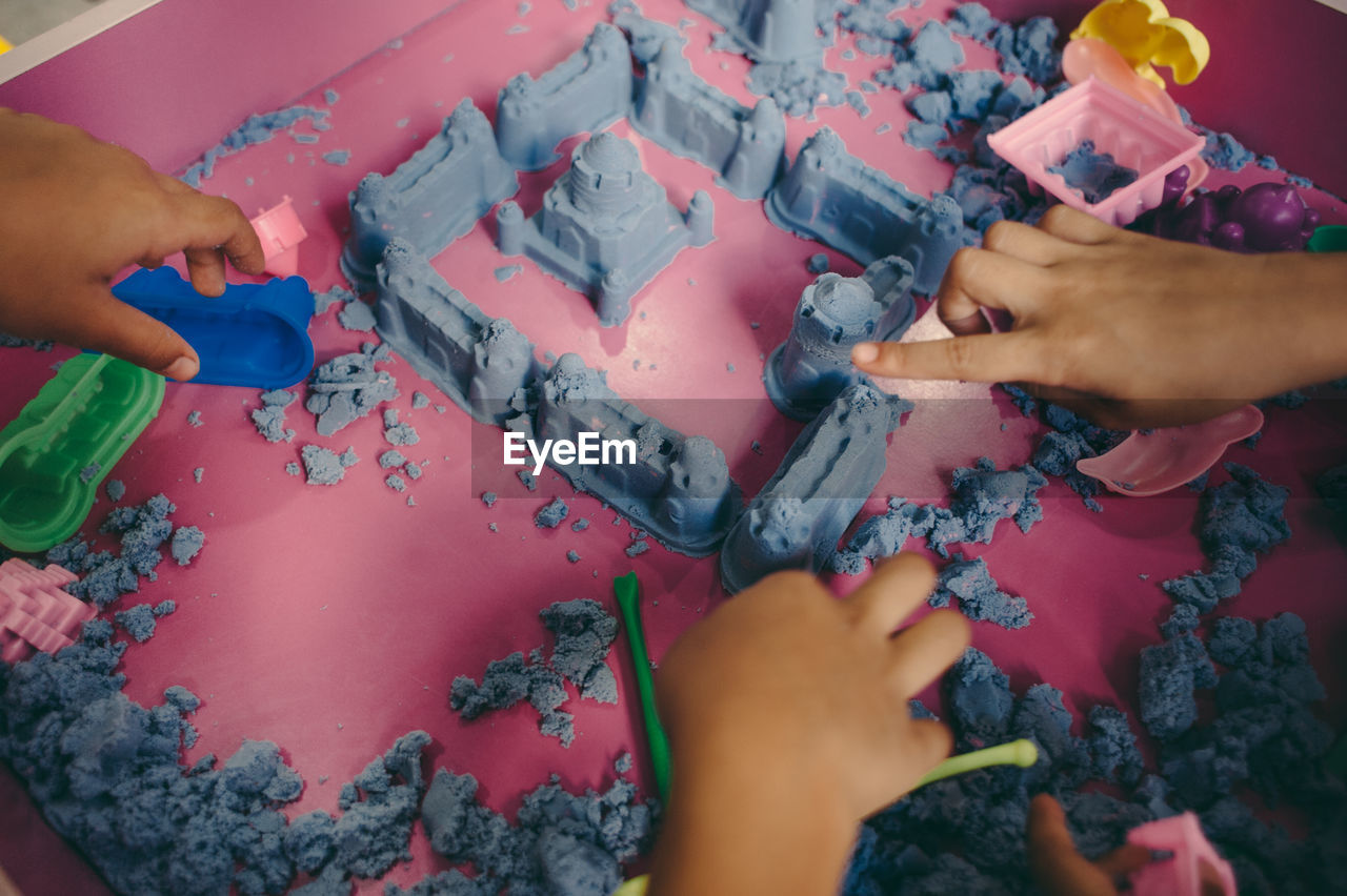 Cropped hands of children making castle from clay