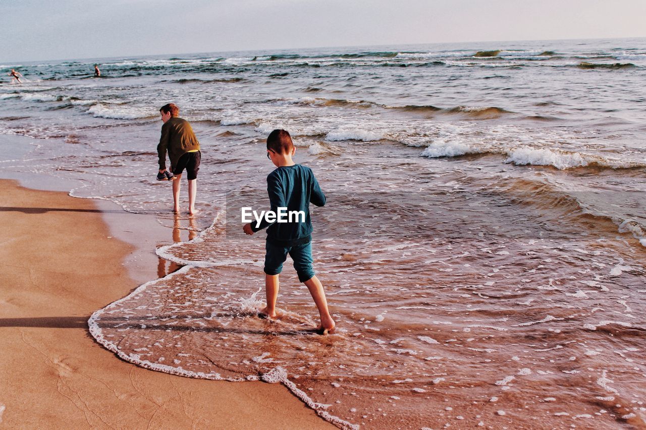 Rear view of siblings standing at beach