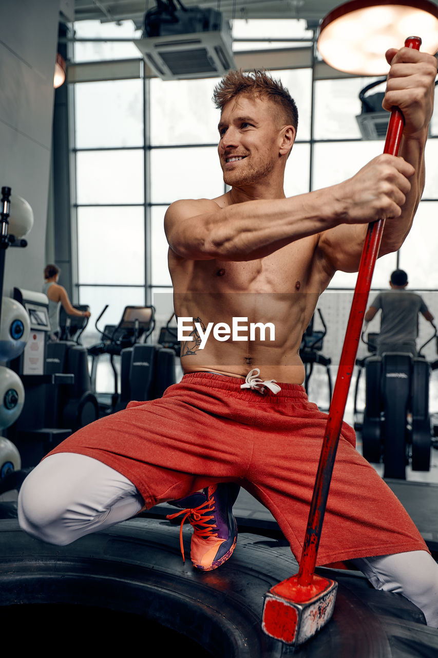 portrait of shirtless man exercising in gym