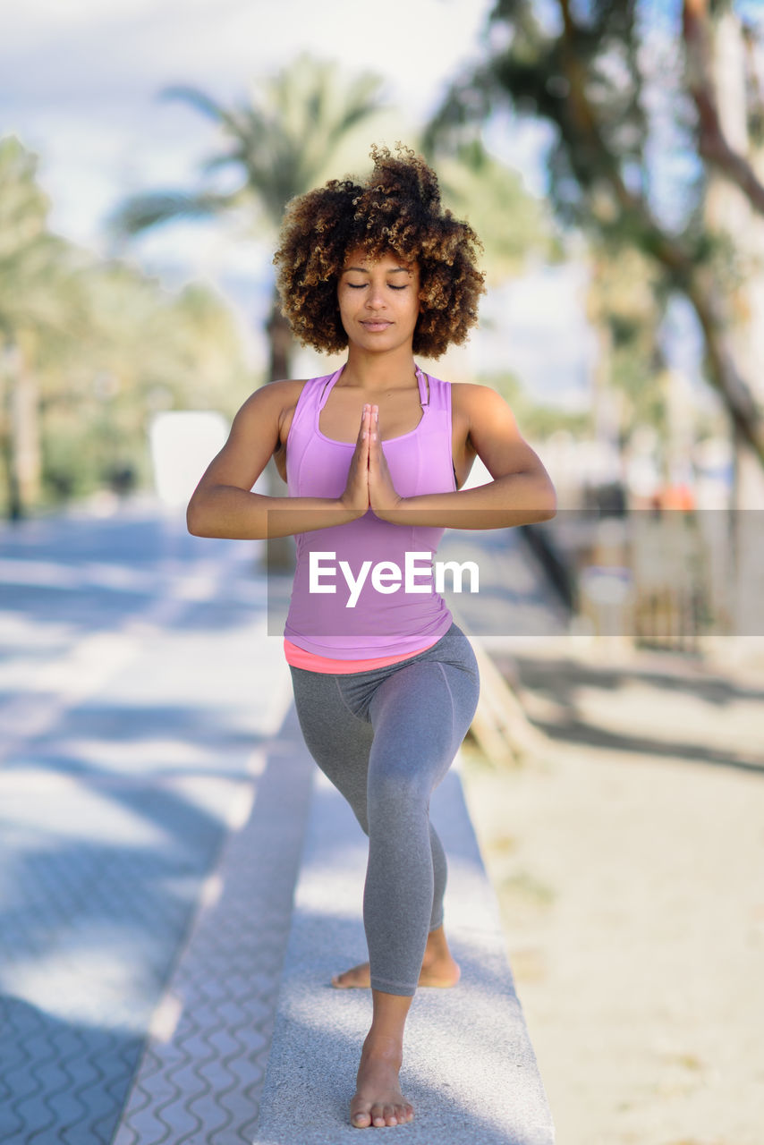 Full length of young woman performing yoga outdoors