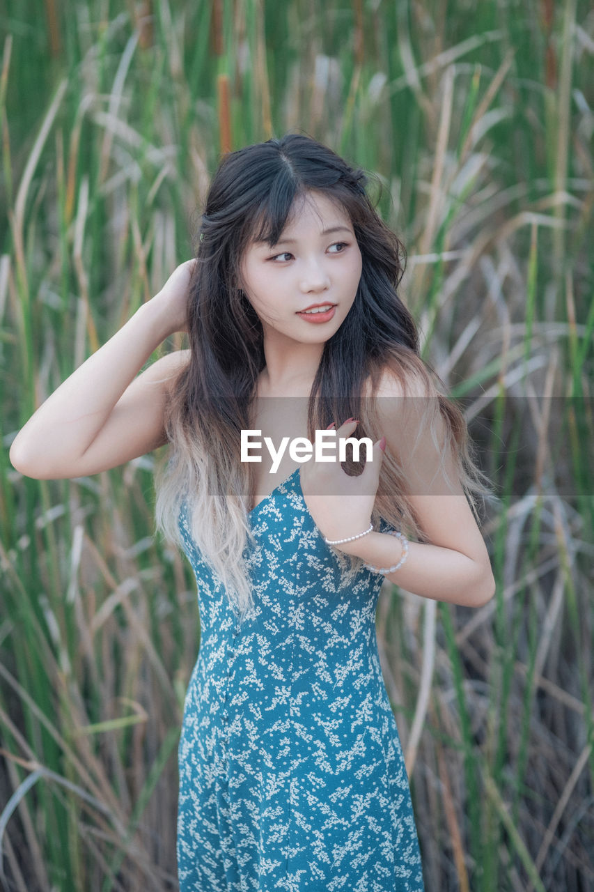 Portrait of young woman standing against plants