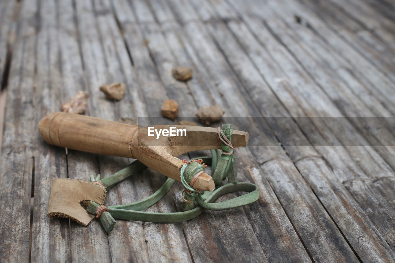 Close-up of slingshot and stones on wooden table