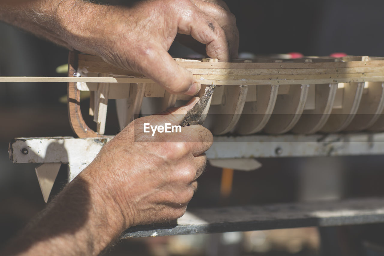 Close-up of man working on wooden boat model