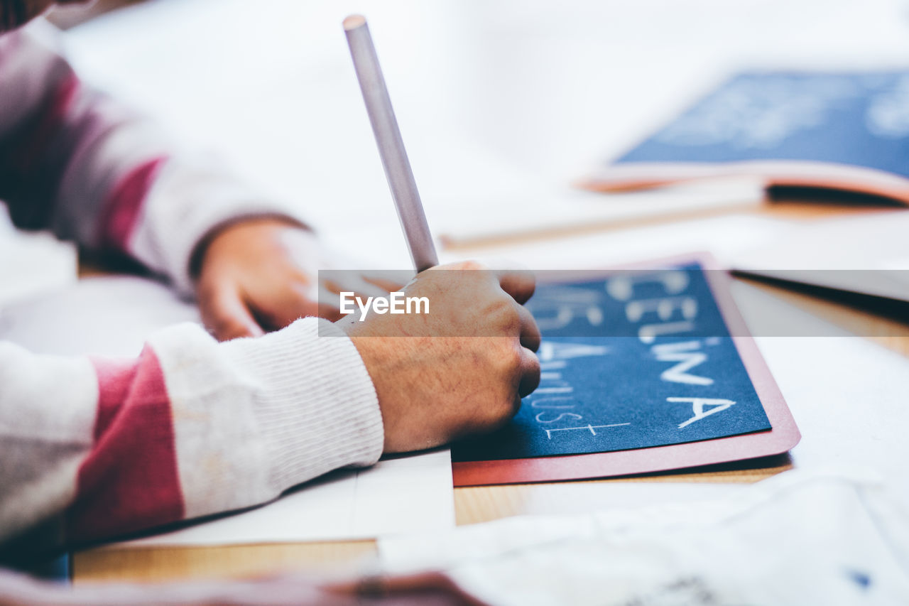 Close-up of childrens hand writing in school  