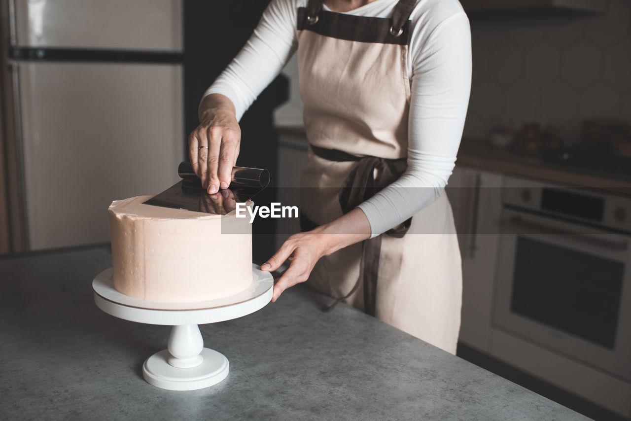 Woman making creamy birthday cake in kitchen closeup. holiday time. selective focus.