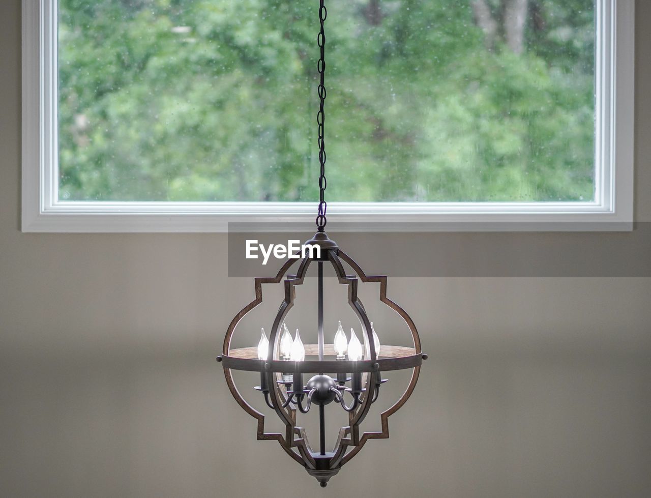 Close-up of illuminated lighting equipment hanging against window at home