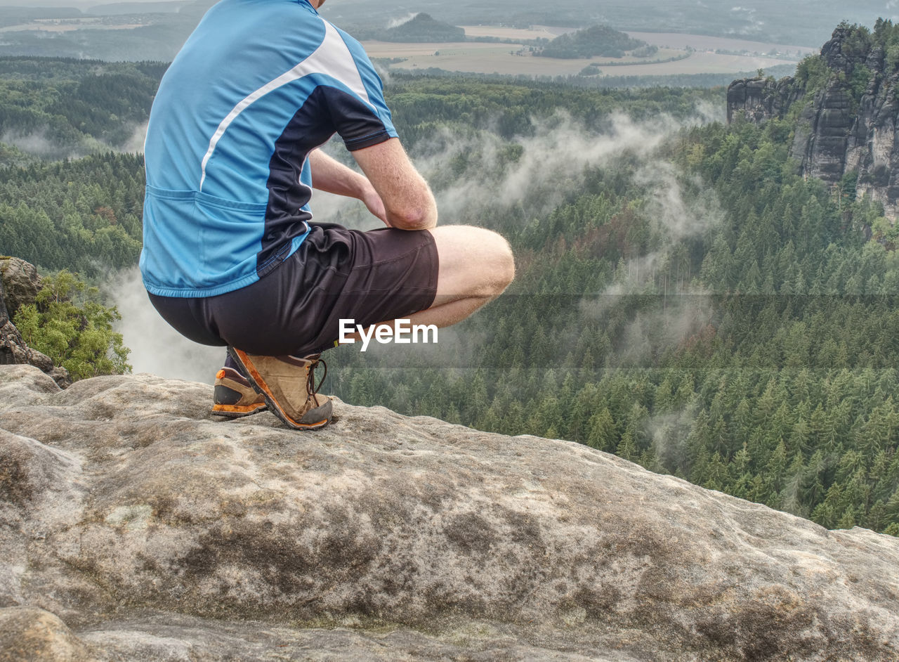 Hiker legs hiking in fall nature enjoy view. feets in trekking shoes and legs short running trousers