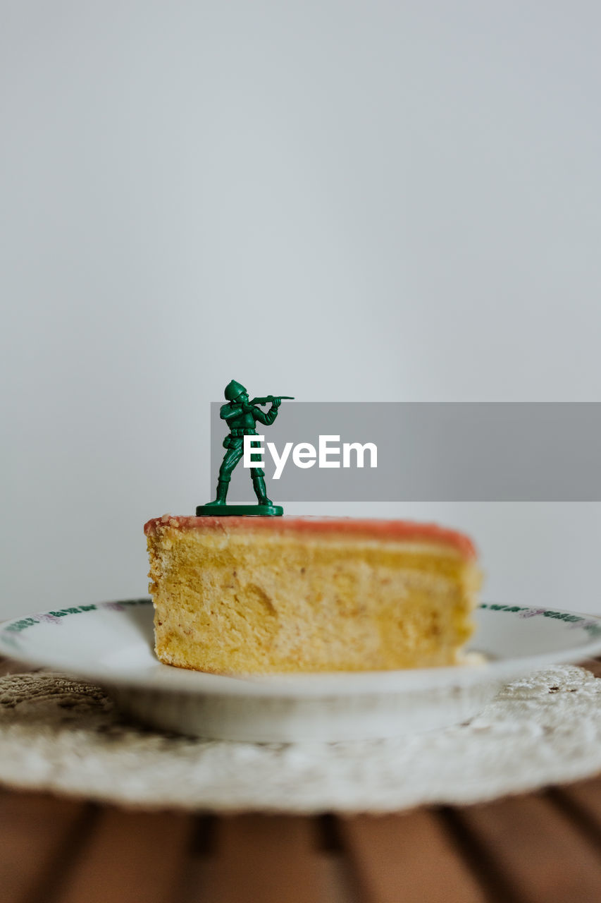 Toy soldier standing on the top of a piece of cake - close up of figurine aginst white background