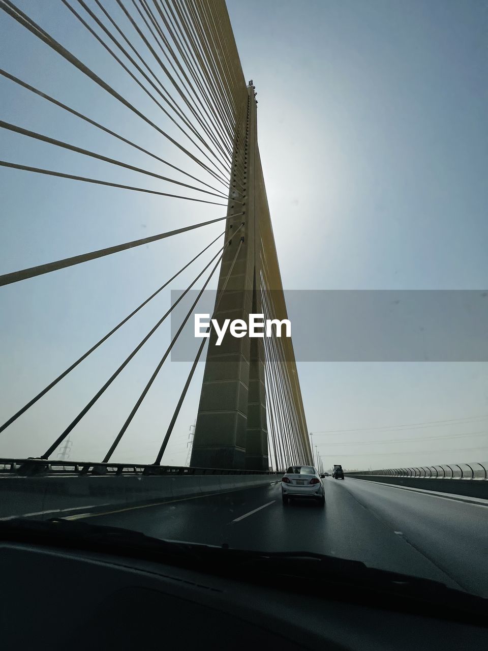 transportation, architecture, cable-stayed bridge, built structure, bridge, sky, city, car, motor vehicle, line, travel, mode of transportation, road, nature, suspension bridge, no people, travel destinations, building exterior, sunlight, land vehicle, outdoors, light, blue, day, water, street